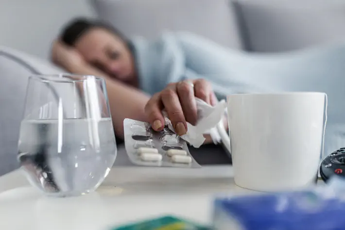 Woman grabbing pills on bedside table.